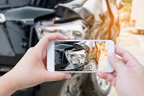 Female hold mobile smartphone photographing car accident for insurance. Concept image of “5 Collision Repair Myths & Misconceptions” | Harv’s Auto Body Repair in Iowa City, IA.