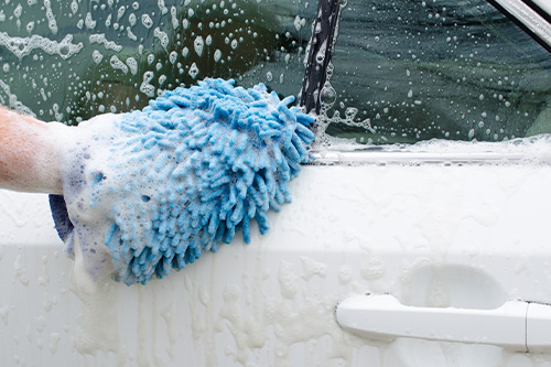 Car wash by hand, with soap suds, bubbles, and mitt. Concept image of “The Do's and Don'ts of Car Detailing” | Harv’s Auto Body Repair in Iowa City, IA.