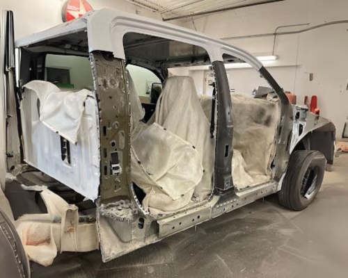 Collision center near Iowa City, IA Harv’s Auto Body. Image of white four door pickup truck in the shop with doors off for collision repair and repaint.