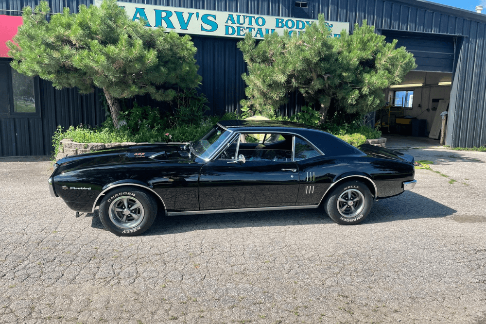 auto body lifetime guarantee, auto body repair in Iowa City, IA at Harv's Auto Body Repair. Image of a beautifully restored black Pontiac Firebird parked in front of Harv's Auto Body Repair.