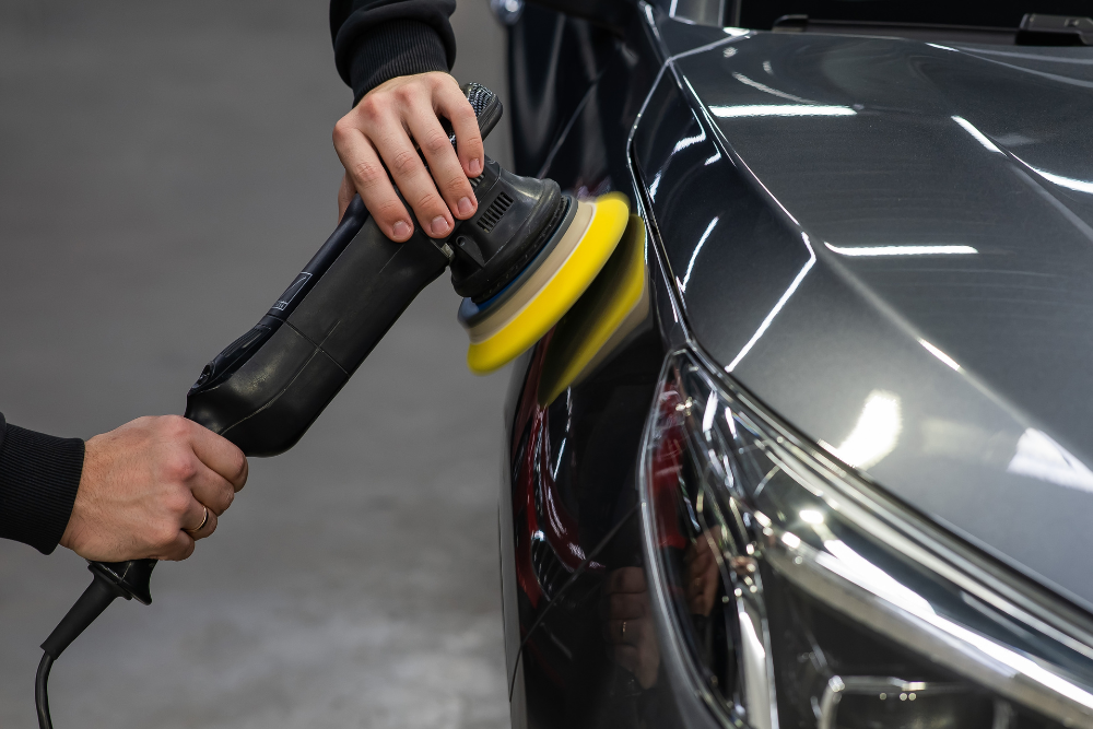 Auto Detailing in Iowa City, IA At Harv's Auto Body Repair. Detailer using a dual-action rotary buffer to polish a dark gray car fender